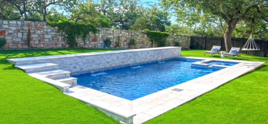 pool with white marble tiles in a green lawn built by creative pools and spas