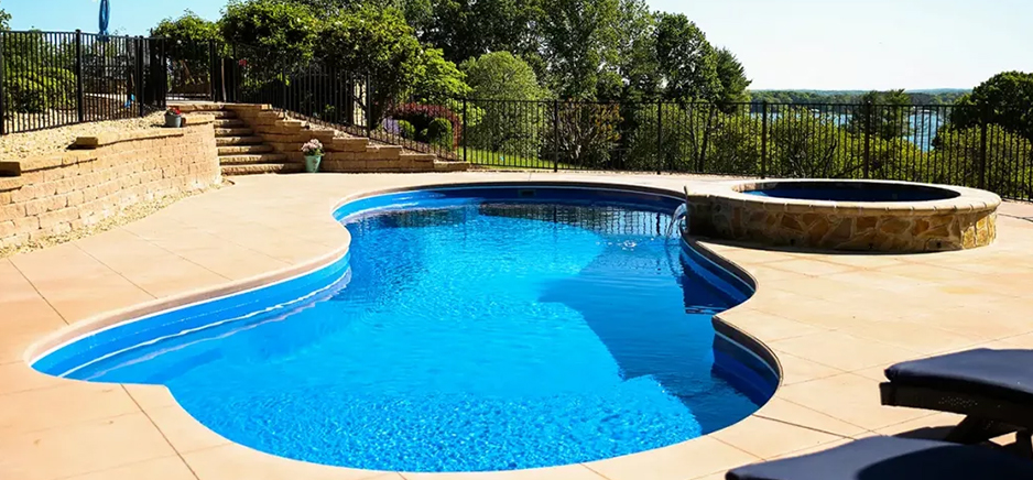 irregular shape pool with spa near green trees built by creative pools and spas